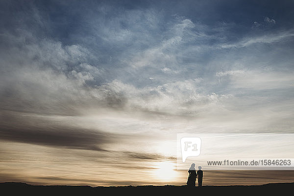 Silhouette of young mother and school-aged son walking at beach