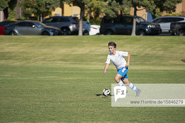 Teenager-Fussballspieler trainieren mit einem Ball in einem Park
