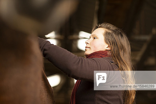 junge Frau mit einem Pferd in einem Pferdestall