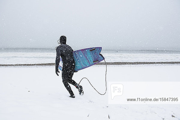 Mann geht im Winterschnee surfen