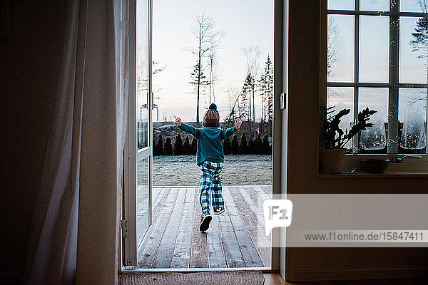 young boy running out the backdoor to play outside in winter