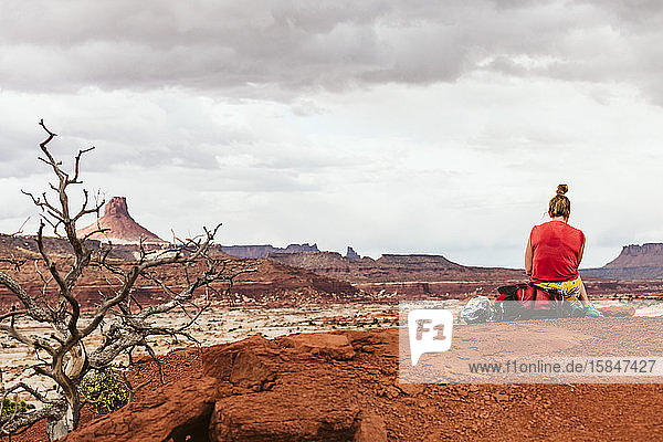 female backpacker sits on her pack while taking a break in utah desert