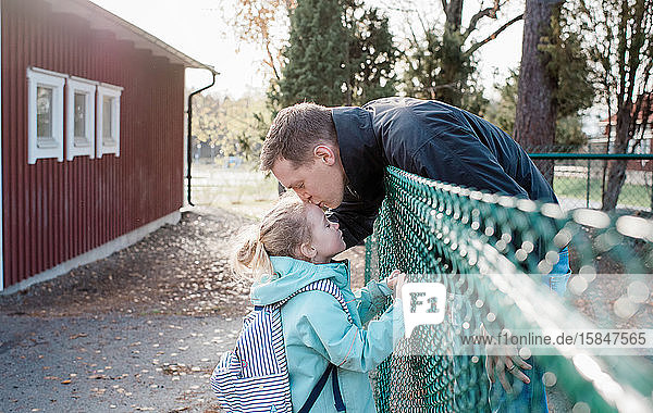 Vater  der seine Tochter zum Abschied am Schultor küsst