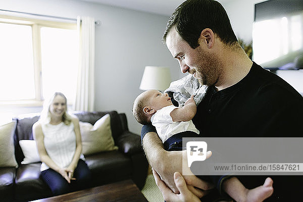 Zum ersten Mal hält der Vater sein Neugeborenes  während die Mutter zuschaut