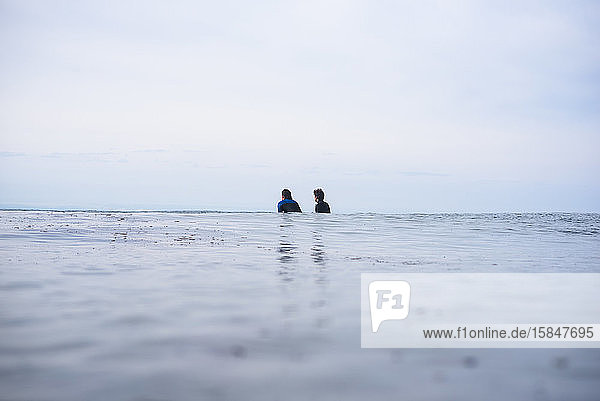 Two friends waiting for waves in the ocean