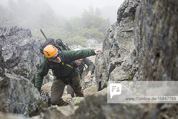 Bergsteiger klettert eine felsige Schlucht in der Coast Mountain Range hinauf.