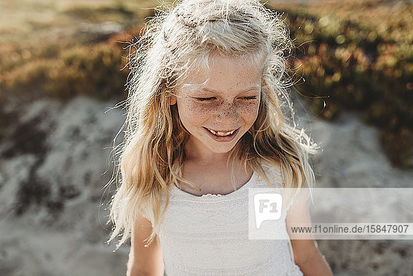 Portrait of young school age girl with freckles looking away on beach