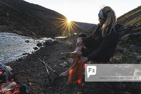 Wanderer trocknet ihre Füsse nach Überquerung des Gletscherflusses