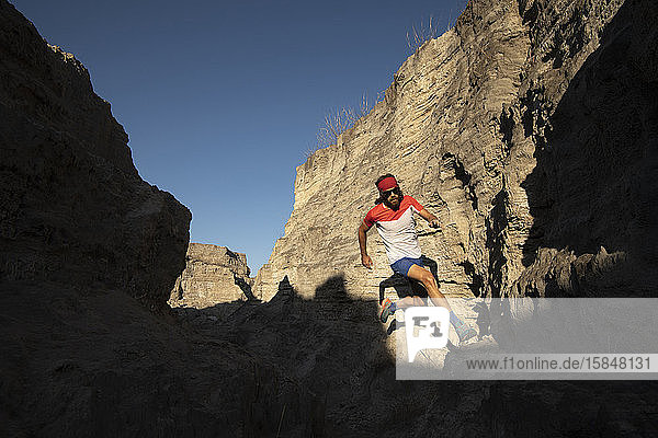 One man trail running on a small canyon with high contrast light