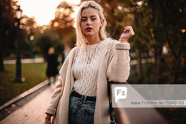 Porträt einer selbstbewussten jungen Frau die im Herbst im Park steht