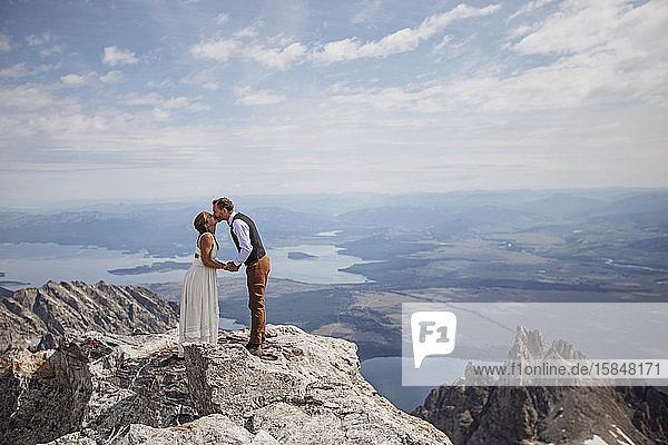 Braut und Bräutigam küssen sich auf dem Gipfel eines Berges in Wyoming