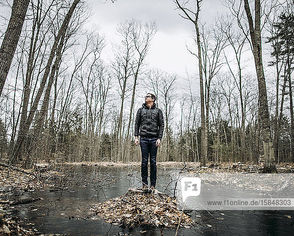 Großer Mann steht auf einem Stumpf mitten im Sumpf an einem kalten  bewölkten Tag
