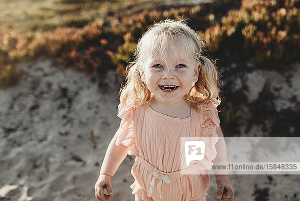 Portrait of young toddler girl with pigtails smiling on beach