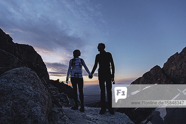 A couple hold hands while hiking in the mountains at dawn  Wyoming