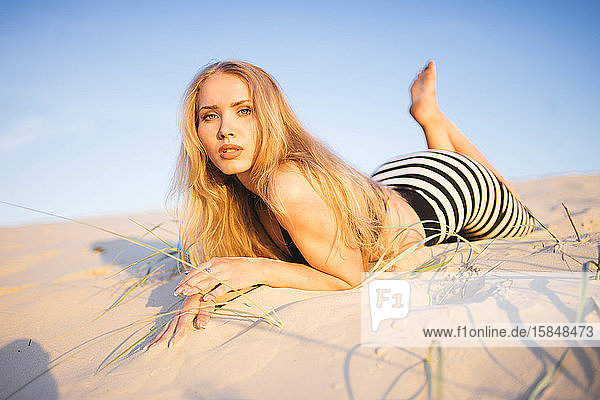 Frau liegt an einem sonnigen Tag an einem Sandstrand