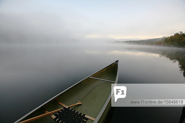 Ein schnittiges Kanu  das an einem Dock an einem ruhigen Teich in Maine festgemacht ist.