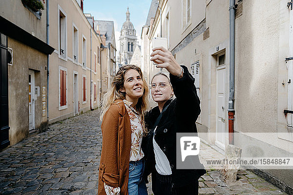 Young women taking selfie in a typical french town's street
