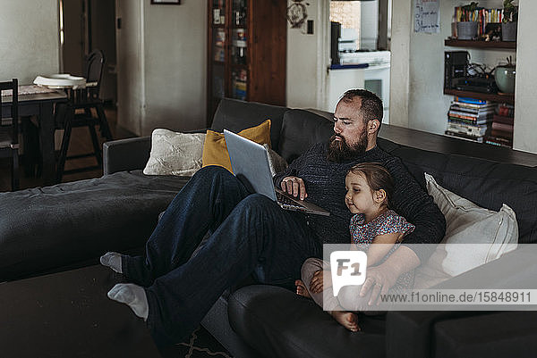 Father working from home with young daughter during isolation