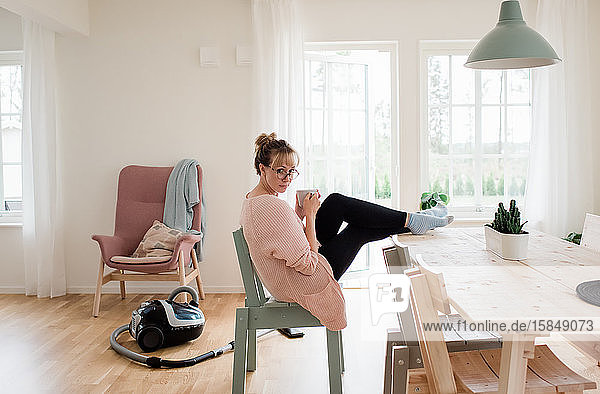 woman sat at home looking drinking a cup of tea at home