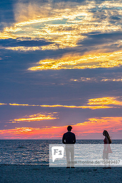 Young couple on beach during beautiful summer sunset.
