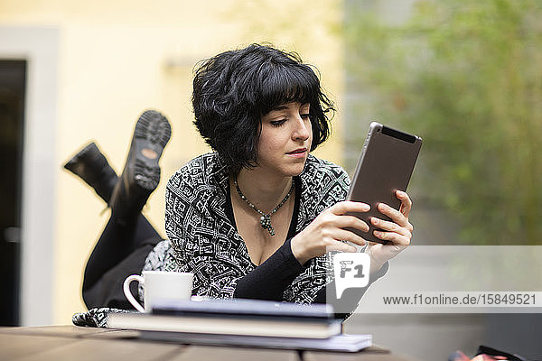 junge Frau mit Laptop  die draußen arbeitet und auf einem Tisch liegt