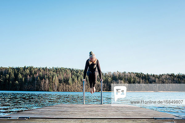 Frau balanciert auf Stufen  die sich in Schweden auf das Schwimmen in kaltem Wasser vorbereiten