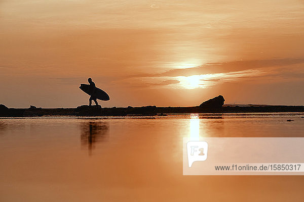 Silhouette eines Surfers bei Sonnenuntergang am Strand