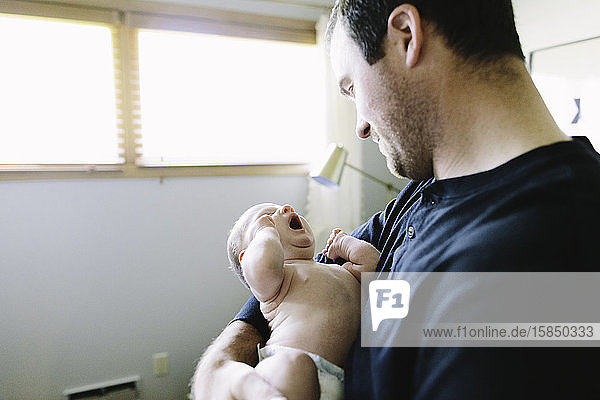 Ein neuer Papa hält seinen müden neugeborenen Sohn
