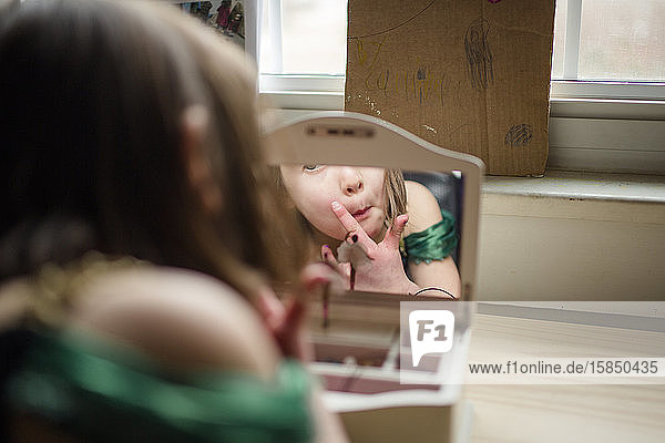 Ein kleines Mädchen betrachtet ihr Spiegelbild in einem Spiegel einer Schmuckschatulle