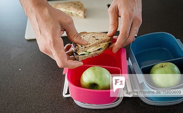 father making a packed lunch box for his kids before school