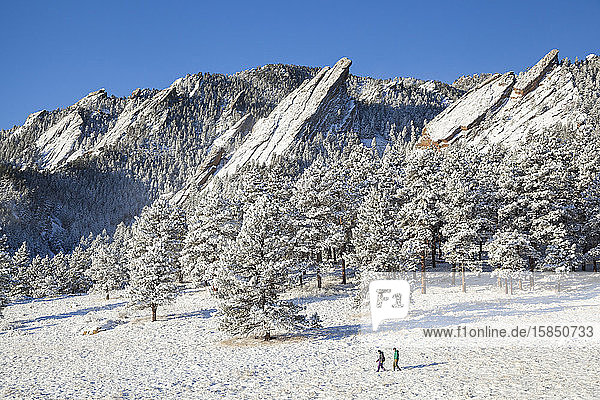 Wanderer überqueren Schneewiese unterhalb von Flatirons oberhalb von Boulder  Colorado
