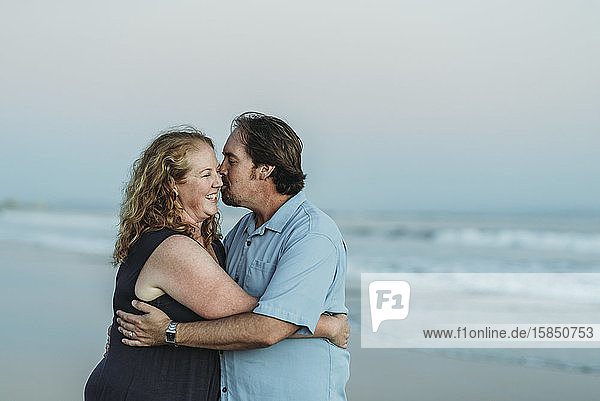 Seitenansicht von Mann und Frau  die sich am Strand küssen