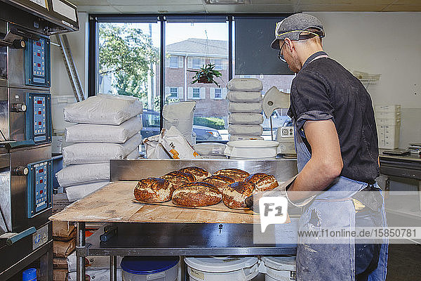 Ein professioneller Bäcker legt Brotschalen auf die Theke in einer Einzelhandelsküche