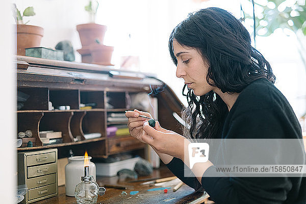 Porträt einer Juwelierin  die im Heimstudio mit kleinen Werkzeugen arbeitet
