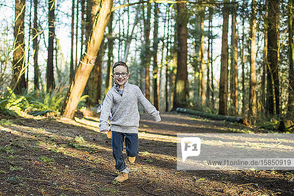 Young boy running through the forest.