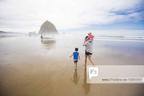 Mother and two kids walk toward Haystack Rock  Cannon Beach.