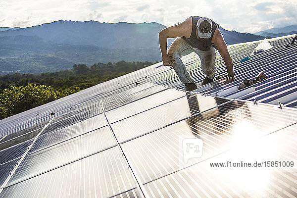 Arbeiter arbeitet sorgfältig an der Sicherung der Sonnenkollektoren auf dem Dach des Gebäudes.