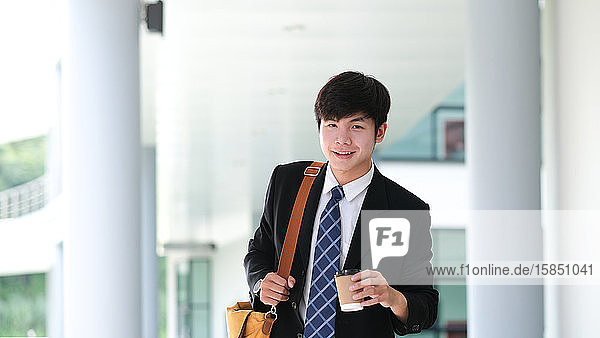 Smiling young businessman holding coffee cup while coffee break.