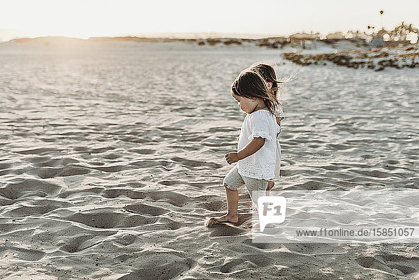 Seitenansicht von jungen Kleinkind-Mädchen  die sich an den Händen halten und am Strand spazieren