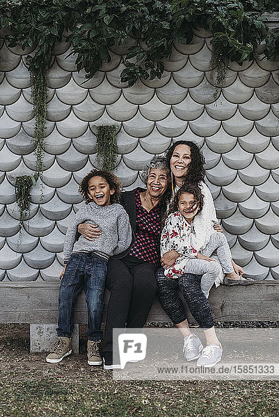 Porträt einer Mehrgenerationen-Familie  die draußen sitzt und lächelt