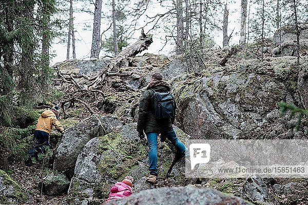 Vater klettert mit seinem Sohn und seiner Tochter beim Wandern an Felsen