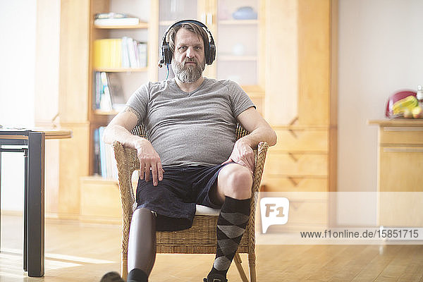 älterer Mann mit Beinprothese  der auf einem Stuhl Musik hört
