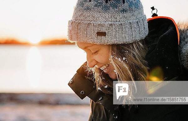 Porträt einer lachenden Frau  die im Winter draußen mit Schnee im Haar lacht