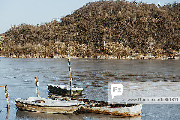 Eisige Landschaft auf dem Land  drei Boote auf einem zugefrorenen See