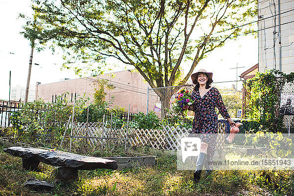 glückliche Frau  die im städtischen Garten mit frischen Blumen spazieren geht