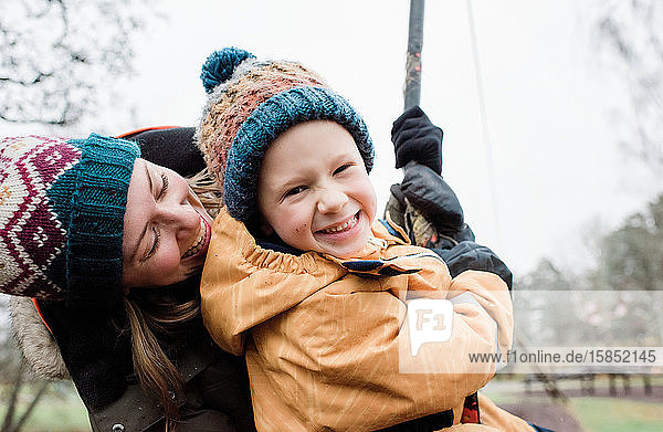 Porträt von Mutter und Sohn  die im Winter im Regen in einem Park spielen