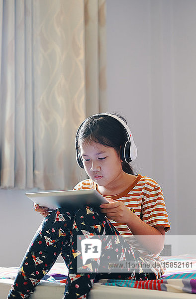 Mädchen benutzen ein Tablett und hören Musik mit Kopfhörern