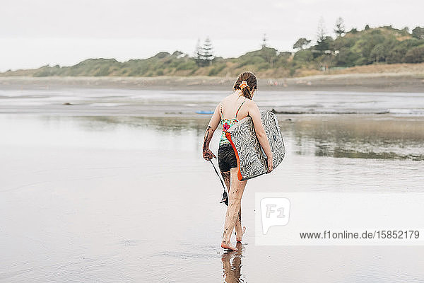 Junges Mädchen hält ein Boogie-Board am Strand