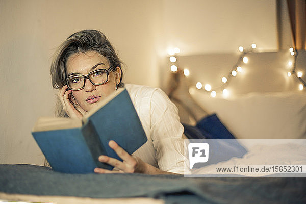 junge Frau liest ein Buch auf einem Bett