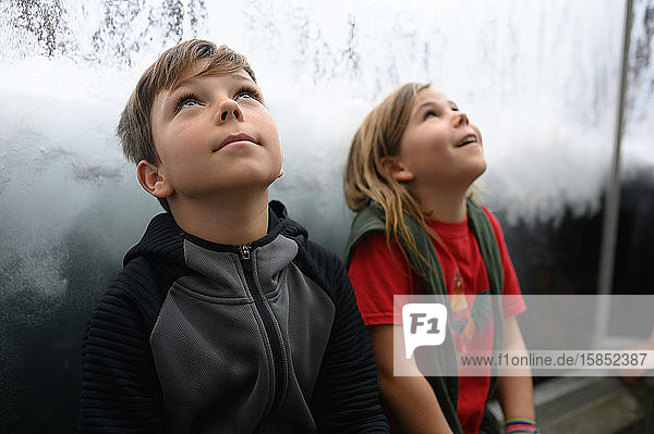 Two children seated looking up to the sky with curiosity
